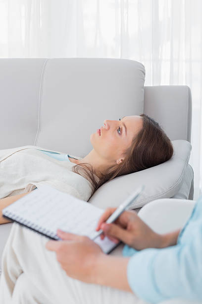istock Worried woman lying on the couch while psychologist writing 499406227
