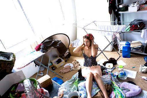 beautiful woman is expressing panic in her really messy room