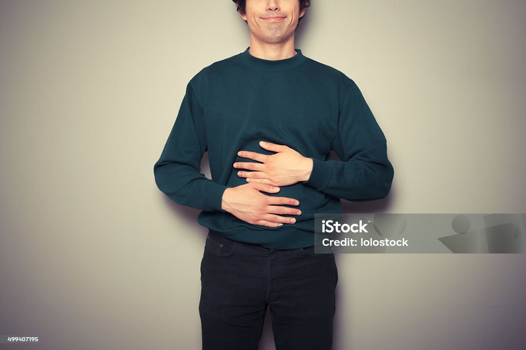 Young man rubbing his stomach A young man is rubbing his stomach Hungry Stock Photo