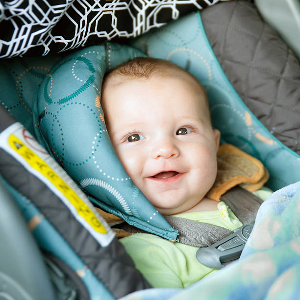 Happy baby buckled into rear-facing car seat stock photo