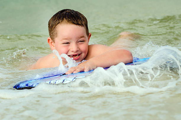 Child surfing on bodyboard at beach
