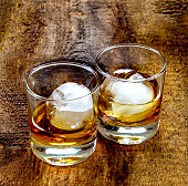 Cocktail glasses filled with whiskey on rustic background.