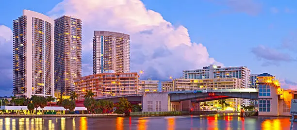 Hallandale Beach Florida, modern buildings and colorful illuminated bridge at sunset