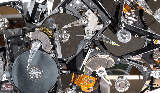 A pile of hard drives being recycled. The tops have been removed, and the drives are dusty and dirty. View is from the top.