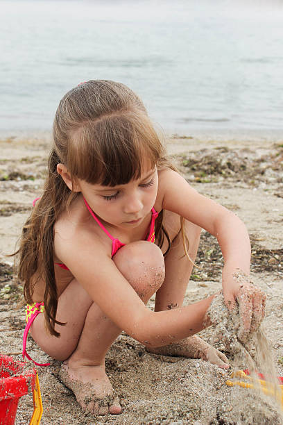 istock Girl playing with sand on the sea shore 499433449