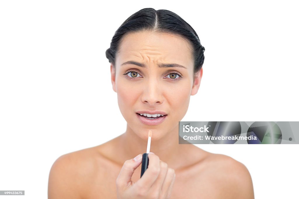Young brunette applying lip gloss Young brunette applying lip gloss on white background 20-29 Years Stock Photo