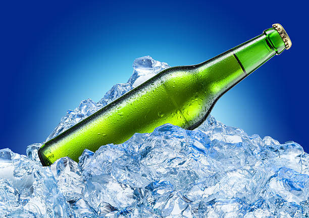 Bottle of beer with drops in ice. Isolated on blue.