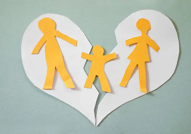 Paper cutout family split apart on a paper heart - divorce concept