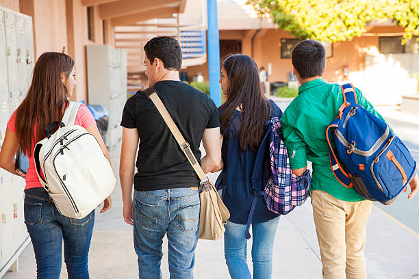 Students in a school hallway Rear view of a bunch of high school students walking down the hallway teenagers only stock pictures, royalty-free photos & images