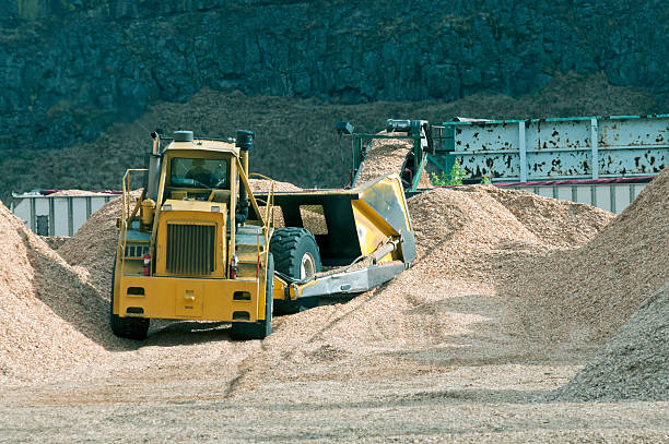 istock Tractor pushing wood chips onto barge at mill 499452155
