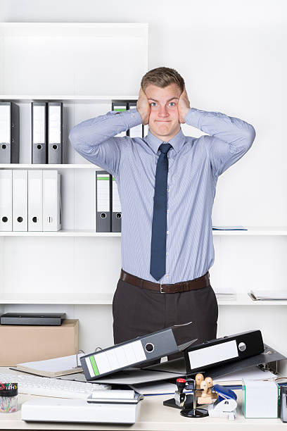 istock Young despaired man is standing in front of many files 499454941