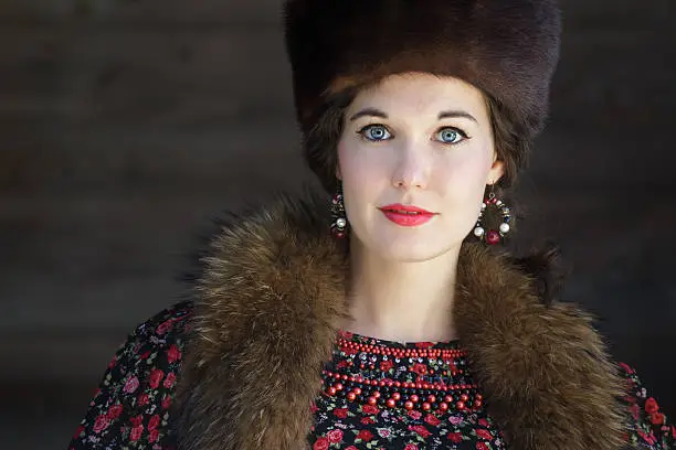 Head and shoulders portrait of Russian beauty with blue eyes wearing fur Cossack hat