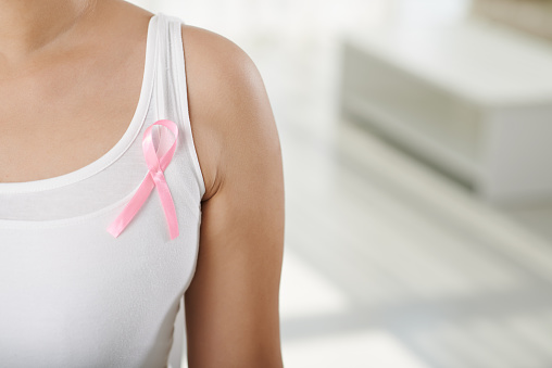 Cropped image of woman wearing pink ribbon, symbol of breast cancer awareness