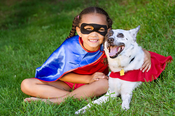 Girl and pet dressed up as super heroes stock photo