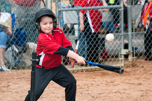 Young baseball player hitting ball off a tee during game