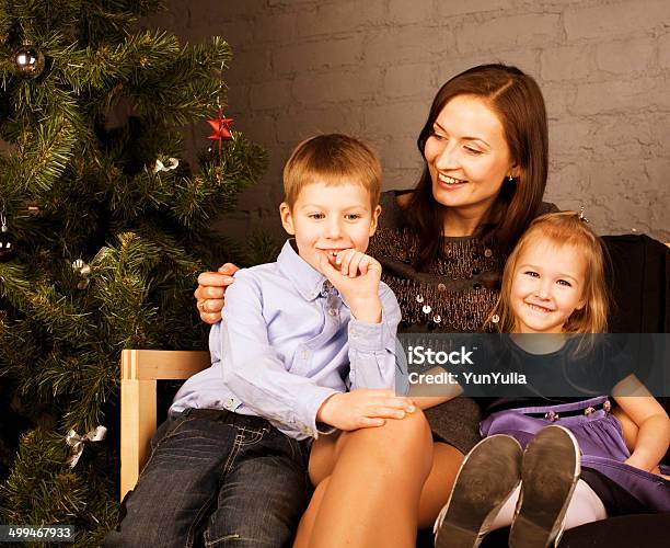 Happy Family At Christmas Tree Stock Photo - Download Image Now - Adult, Assistance, Boys