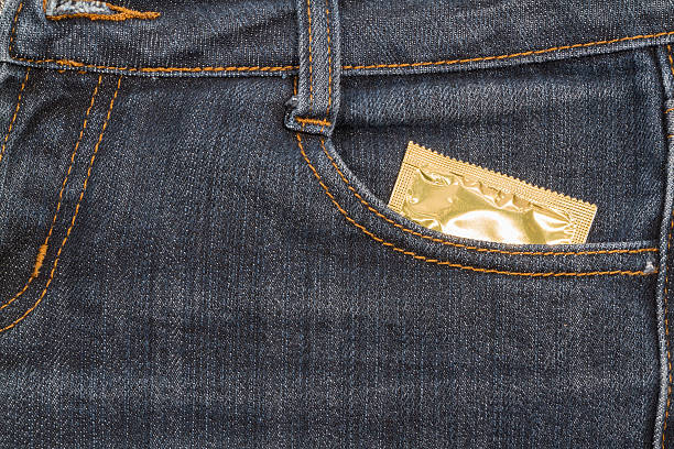 condón en jeans pocket. fondo. - condom sex sexually transmitted disease aids fotografías e imágenes de stock