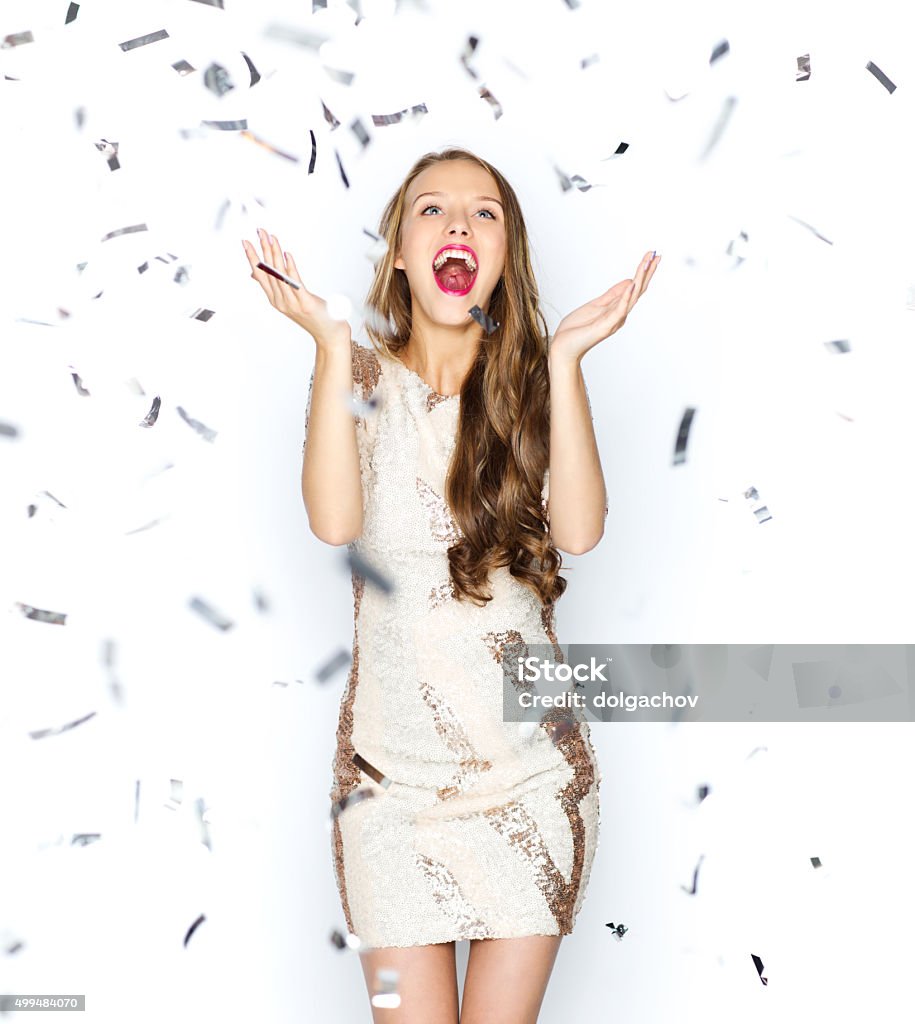 happy young woman or teen girl in fancy dress people, holidays, emotion and glamour concept - happy young woman or teen girl in fancy dress with sequins and confetti at party Teenage Girls Stock Photo