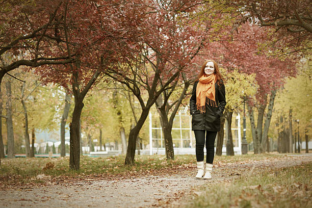 istock redhead girl walk on pathway in city park, fall season 499487526