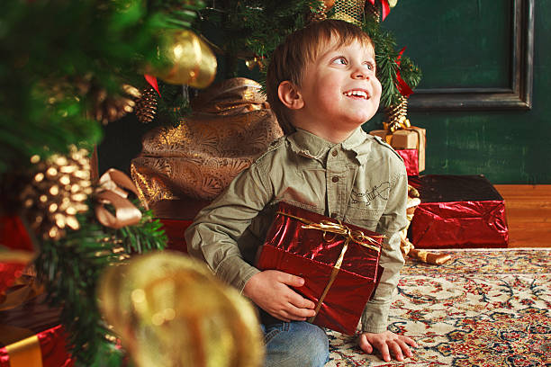 child sitting under the Christmas tree with gifts