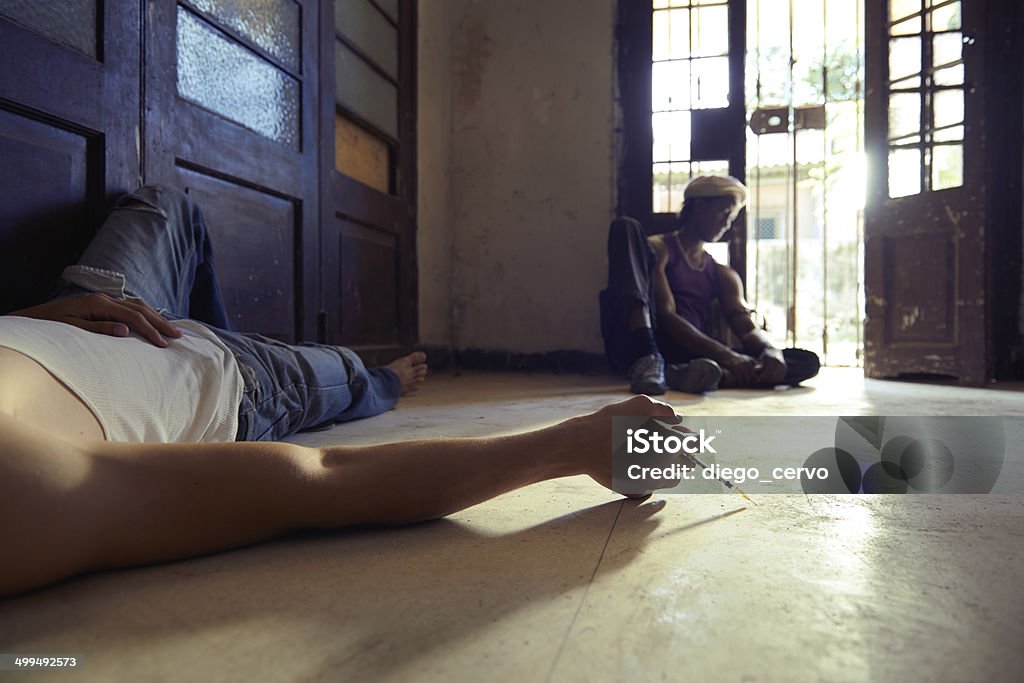 Drug abuse with people using syringe and injecting heroine African american man and caucasian guy in overdose, injecting heroine with syringe and lying on pavement Addict Stock Photo