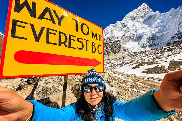 Young woman taking selfie in Himalayas, next to the signpost "Way to Mount Everest Base Camp" . She is wearing blue jacket and holding a tablet. Mount Everest National Park. This is the highest national park in the world, with the entire park located above 3,000 m ( 9,700 ft). This park includes three peaks higher than 8,000 m, including Mt Everest. Therefore, most of the park area is very rugged and steep, with its terrain cut by deep rivers and glaciers. Unlike other parks in the plain areas, this park can be divided into four climate zones because of the rising altitude. The climatic zones include a forested lower zone, a zone of alpine scrub, the upper alpine zone which includes upper limit of vegetation growth, and the Arctic zone where no plants can grow. The types of plants and animals that are found in the park depend on the altitude.http://bem.2be.pl/IS/nepal_380.jpg