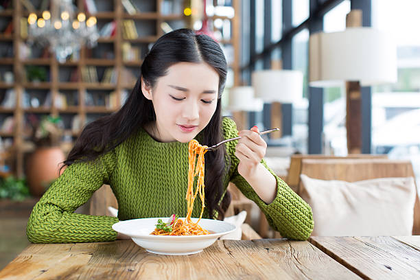 beautiful chinese female student, at the Italian restaurant to eat noodles