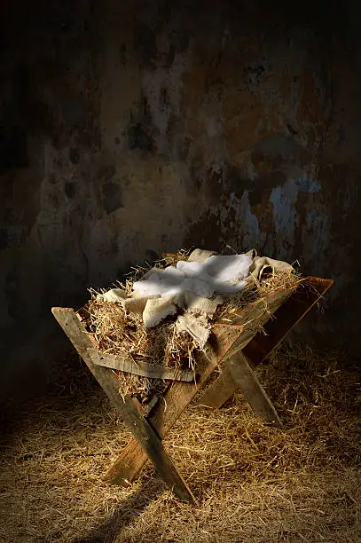 Empty manger with shadow of cross in old dirty barn