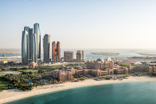 View towards Dubai marina buildings across the sea and beach on a sunny afternoon