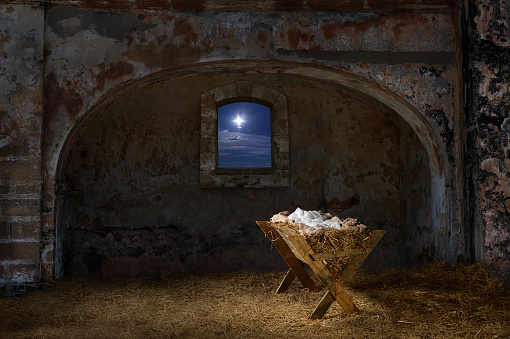 Empty manger in old barn with window showing the Christmas star
