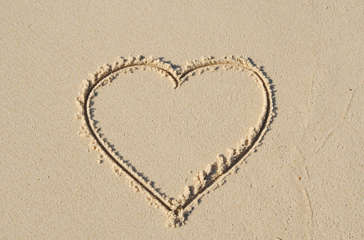 Heart with loop drawn in the wet sand , soon to be erased by the waves