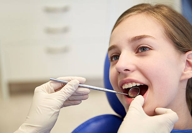 istock hands with dental mirror checking girl teeth 499514620