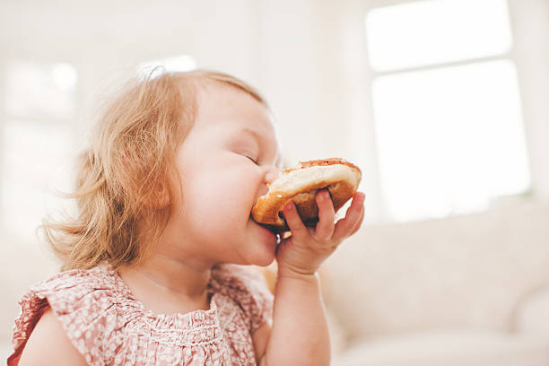 cute baby girl eating cinnamon bun - cinnamon buns people bildbanksfoton och bilder