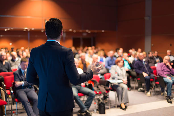 a man speaking at a business conference - presentatie stockfoto's en -beelden