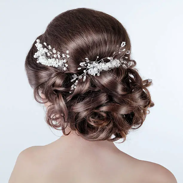 Brown hair styling. Brunette girl with curly hairstyle with barrette. Bride photo