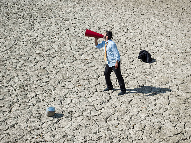 istock Lost businessman in desert looking for help via megaphone 499535013
