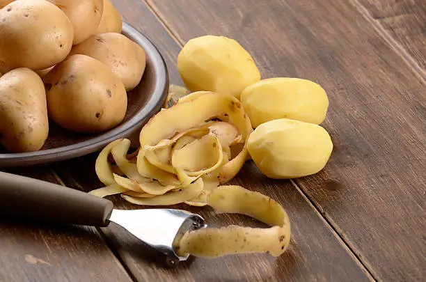 Potatoes being peeled on the wooden table