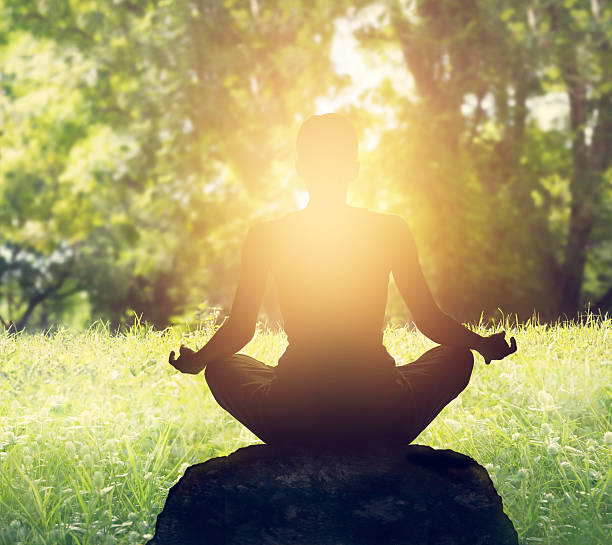 istock woman meditating in green forest on sunset background 499536946