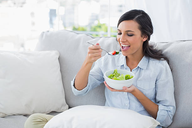 istock Happy woman relaxing on the sofa eating salad 499537385