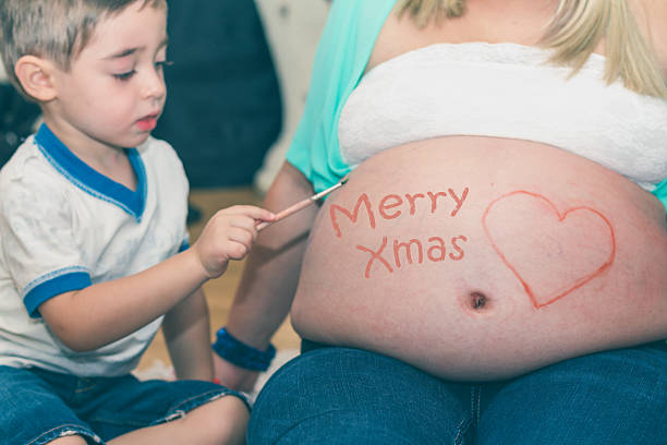 istock Child paints mom's belly - Christmas time 499538232