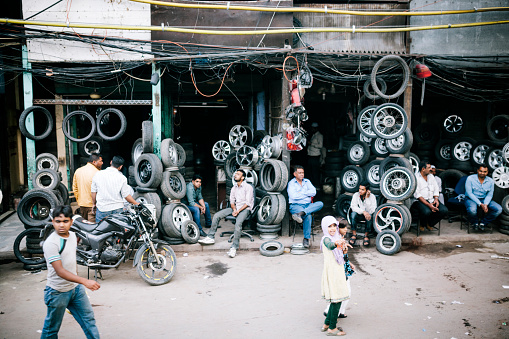 Delhi, India - March 11, 2014: Vehicle wheels surrounding a garage. Mechanics sit outside waiting for customers, Delhi, India