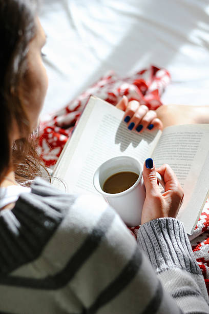 istock Girl in bed with coffee cup reading a book 499539622