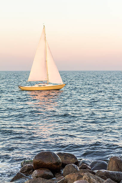 istock yellow sailboat in the ocean with stones in foreground 499541282