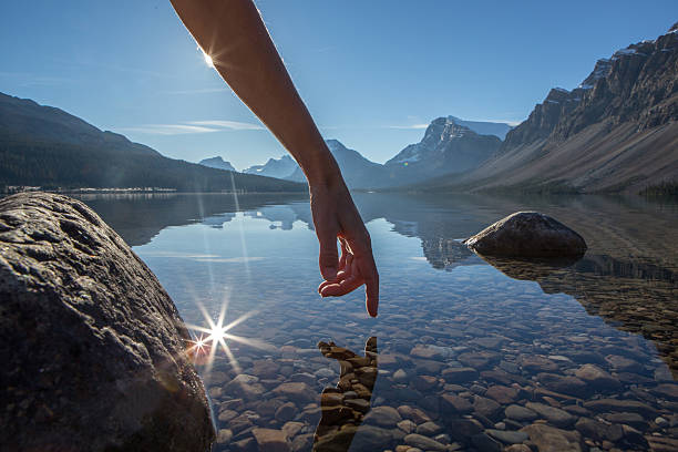 dito tocca la superficie di un lago di montagna, paesaggio spettacolare - bow lake foto e immagini stock