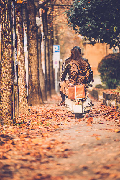 Beautiful woman sitting on motorcycle on country road during autumn day
