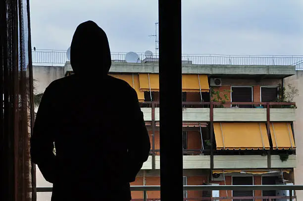 Man looking at city buildings through window.