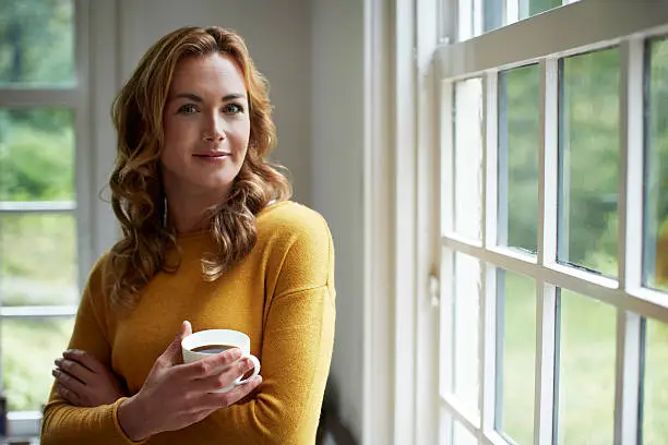 Portrait of confident young woman having coffee in cottage