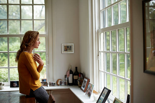 thoughtful woman having coffee in cottage - ausblick stock-fotos und bilder