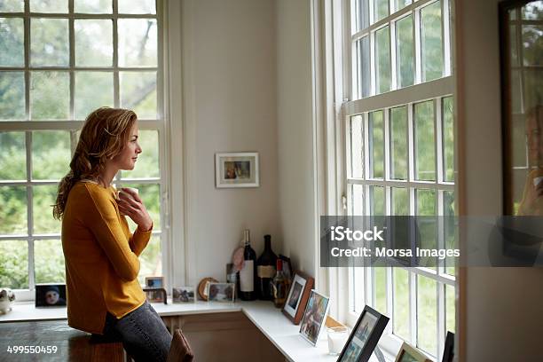 Thoughtful Woman Having Coffee In Cottage Stock Photo - Download Image Now - One Woman Only, Contemplation, Looking Through Window
