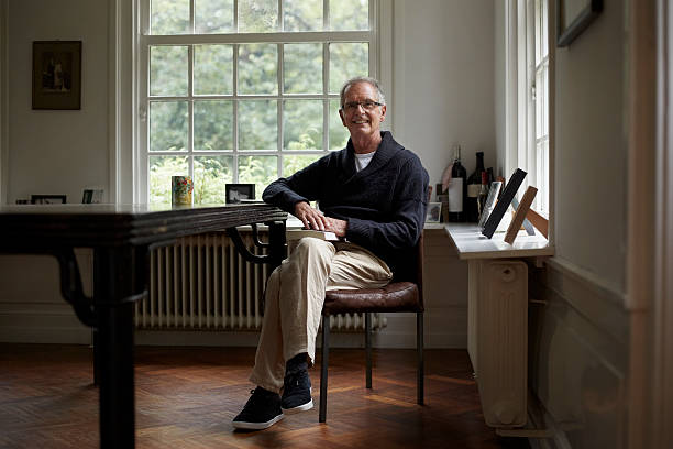 portrait of senior man sitting in cottage - full length windows fotografías e imágenes de stock